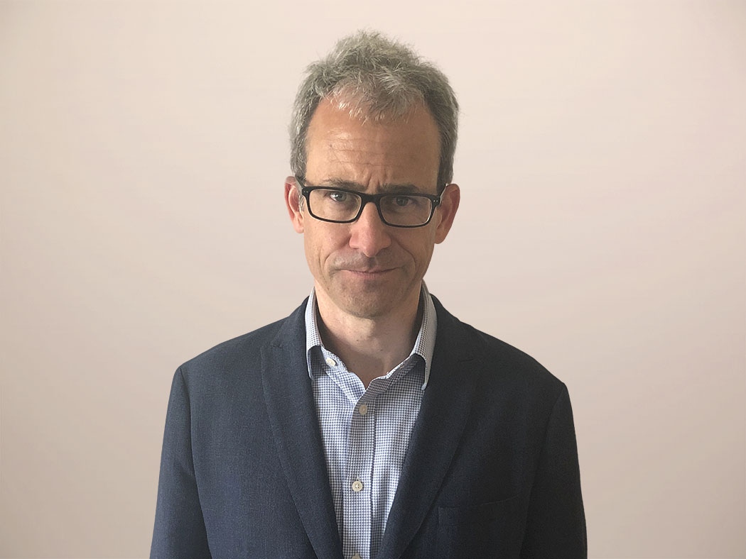 A professional headshot of a man in a suit